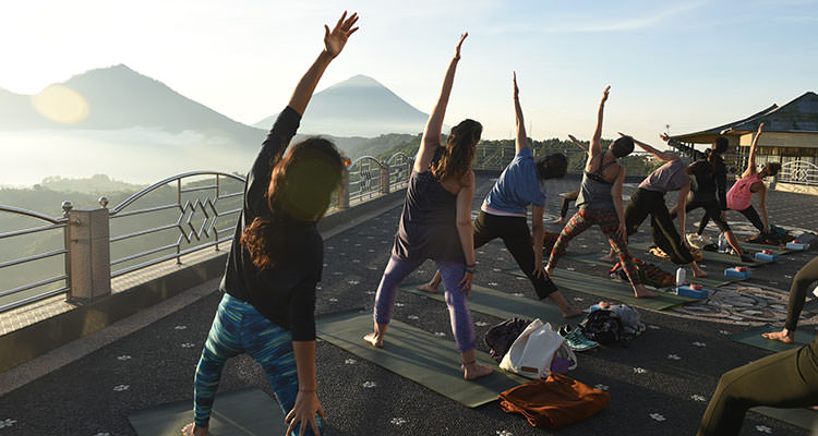 Sunrise yoga facing Mount Batur, one of the highlights of your yoga retreat at Oneworld Retreats in Ubud, Bali.
