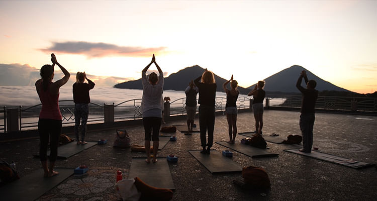 Sunrise yoga facing Mount Batur, one of the highlights of your yoga retreat at Oneworld Retreats in Ubud, Bali.